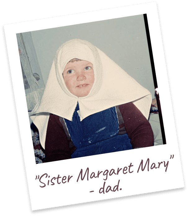 "Sister Margaret Mary" - dad. A toddler in denim overalls with a white towel draped over her head like a wimple.