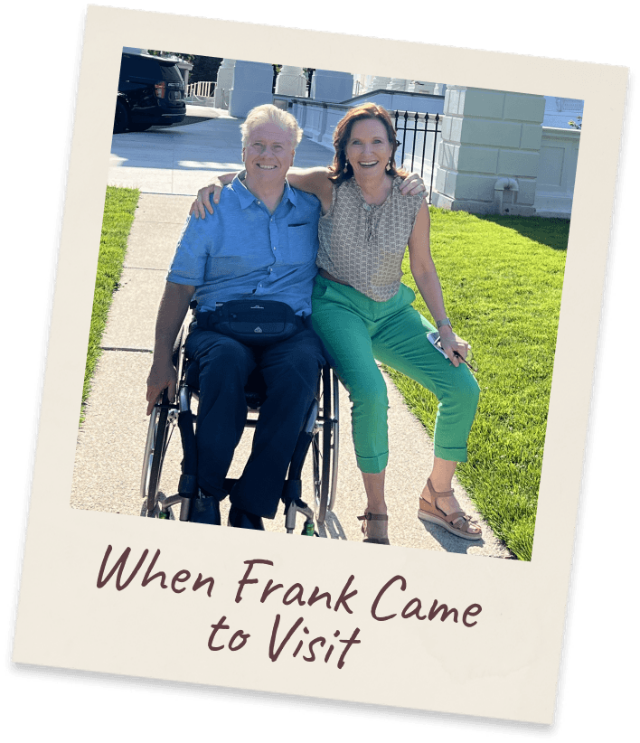 When Frank Came to Visit. Margie standing beside her brother Frank, who is seated in a wheelchair, on a lawn in front of a pale stone building.