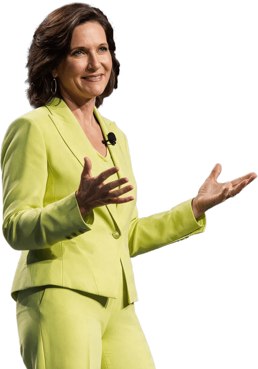 Dr. Margie Warrell on stage in a lime-yellow trouser suit, both hands open at waist height as she speaks