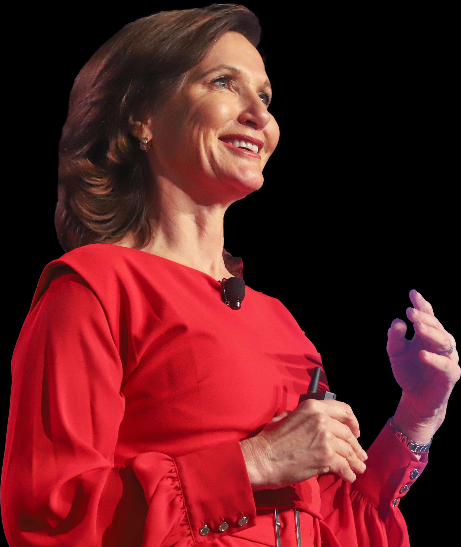 Dr. Margie Warrell on stage in a red dress, smiling, one hand raised as she speaks and a presentation clicker in the other